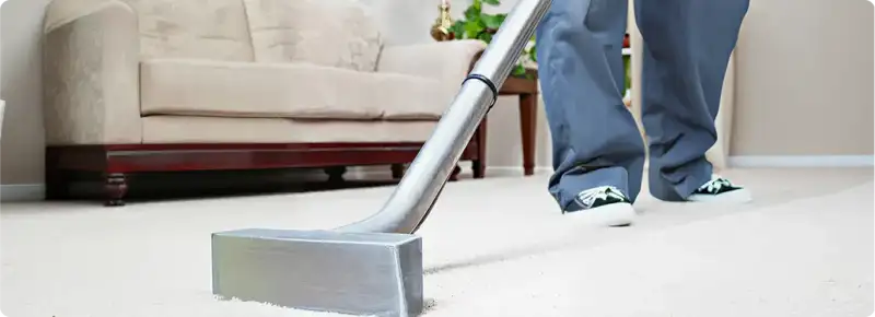 Carpet cleaning technician using a hot-water extraction wand on a light-colored carpet in a living room, Minneapolis, MN.